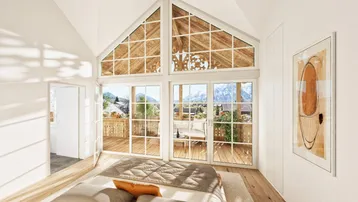 Helles Schlafzimmer mit großen Fenstern, Bergblick und Zugang zu einem sonnigen Balkon.