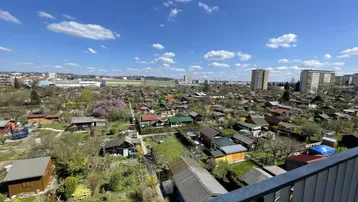 Weitläufiger Blick über Kleingärten und die Stadtlandschaft unter blauem Himmel.