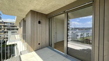 Heller Balkon mit Holzverkleidung und Fliesenboden, bietet einen weiten Blick auf die Umgebung.