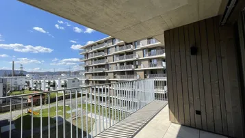 Geräumiger Balkon mit Fliesenboden und Blick auf die umliegenden Gebäude und die Landschaft.