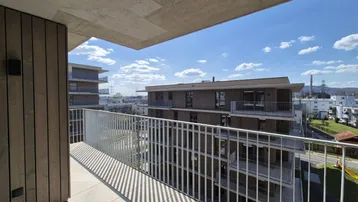 Balkon mit Blick auf moderne Wohngebäude und die Umgebung unter blauem Himmel.