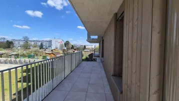 Langer Balkon mit Fliesenboden und Metallgeländer, bietet einen weiten Blick auf die Umgebung.