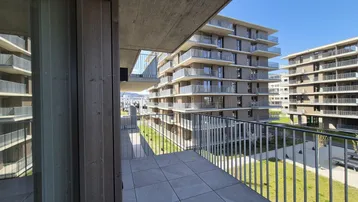Geräumiger Balkon mit Fliesenboden und Blick auf die umliegenden Neubauten und Grünflächen.