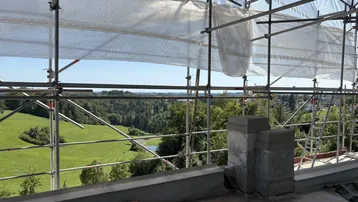 Weitläufiger Blick über grüne Hügel und Wälder von einer Baustelle aus.