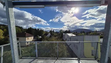 Geräumige Dachterrasse mit Metallgeländer bietet weite Ausblicke auf die umliegende Landschaft und Berge.