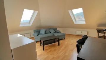 Heller Wohn- und Essbereich im Dachgeschoss mit schrägen Wänden und zwei Dachfenstern.