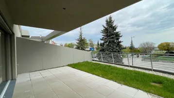 Große, geflieste Terrasse mit Rasenfläche und Blick auf die Umgebung.