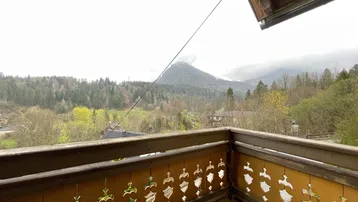 Balkon mit traditionellem Holzgeländer und weitem Blick auf die umliegende Berglandschaft.