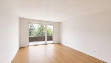 Heller, leerer Wohnraum mit Laminatboden und Zugang zu einem Balkon mit Blick ins Grüne.