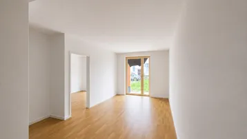 Helles Zimmer mit Holzboden und Zugang zu einem Außenbereich, ideal für Wohn- oder Schlafzimmer.