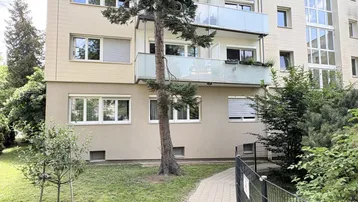 Fassade eines Mehrfamilienhauses mit Balkonen und umgebender Grünfläche.