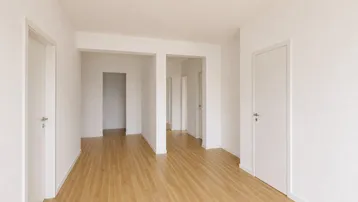 Heller Flur mit neuem Parkettboden und weißen Wänden, der zu weiteren Räumen führt.