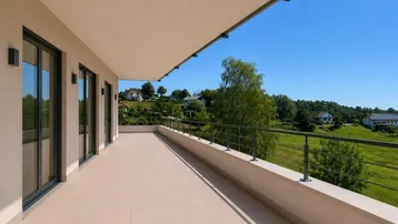 Langer, gefliester Balkon mit Metallgeländer und weitem Blick auf die grüne Landschaft.