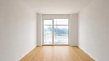 Helles, leeres Zimmer mit weiß gestrichenen Wänden und neuem Holzboden, bereit für die Einrichtung.