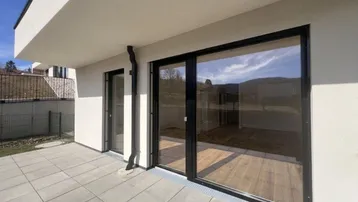 Moderne Terrasse mit großformatigen Fliesen und großen Glasschiebetüren zum Innenbereich.