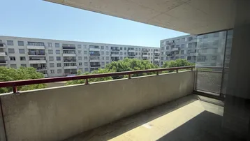 Geräumiger Balkon mit Blick auf umliegende Wohngebäude und grüne Bäume, bietet viel Freiraum.