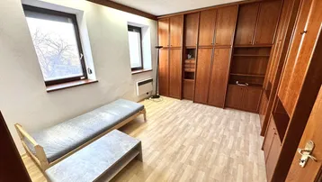 Helles Schlafzimmer mit Holzschränken, Einzelbett und Laminatboden.
