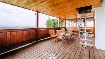 Große überdachte Holzterrasse mit Sitzgelegenheiten und weitem Blick in die Landschaft.