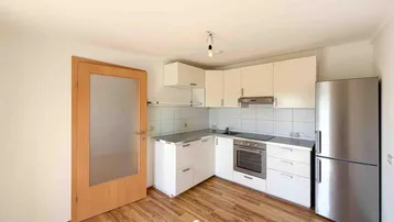 Funktionale Küche mit weißen Schränken, integriertem Backofen und Kühlschrank.