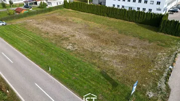 Luftaufnahme eines großen unbebauten Grundstücks mit angrenzender Straße und umliegenden Gebäuden.