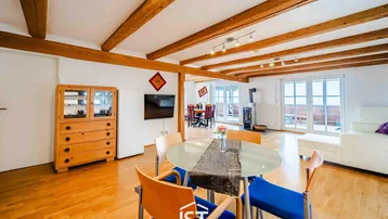 Geräumiger Wohn-Essbereich mit Holzbalken, Parkettboden und Zugang zu einer Terrasse.