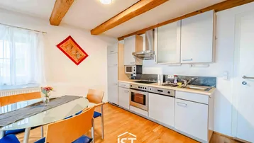 Helle Küche mit Holzbalken, Esstisch und integrierten Geräten, ideal für gemütliche Mahlzeiten.
