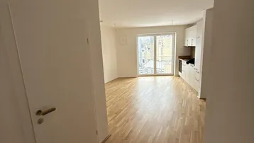 Heller Eingangsbereich führt in einen offenen Wohn-Essbereich mit integrierter Küche und Parkettboden.