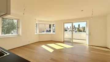 Helles Zimmer mit Holzboden, großen Fenstern und Zugang zu einem Balkon.