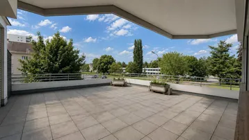 Großzügige Außenterrasse mit weitem Blick auf die grüne Umgebung und die umliegenden Gebäude.