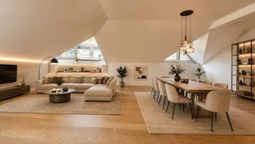 Geräumiger Wohn- und Essbereich im Dachgeschoss mit Holzboden, modernen Möbeln und viel natürlichem Licht.