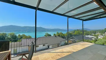 Weitläufige Terrasse mit Glasüberdachung und atemberaubendem Panoramablick auf den See und die Berge.