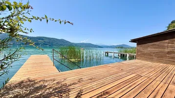 Geräumige Holzterrasse am Seeufer mit direktem Zugang zum Wasser und Bergblick.