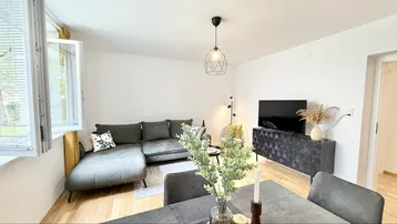 Helles Wohn- und Esszimmer mit modernem Sofa, Esstisch und hellem Holzboden.