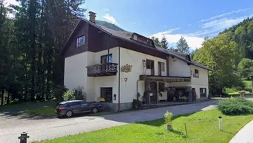 Traditionelles Gebäude mit Balkonen und Blick auf die umliegende Berglandschaft und Wälder.