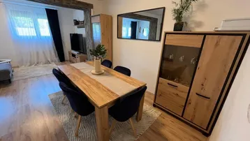 Moderner Essbereich mit Holztisch und dunklen Stühlen, offen zum Wohnzimmer mit Holzboden.