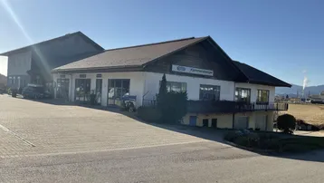 Gebäudeansicht eines Gewerbeobjekts mit großem gepflasterten Vorplatz unter blauem Himmel.