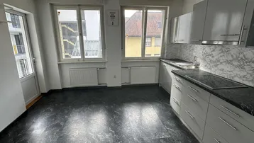 Küche mit grauen Schränken, dunkler Arbeitsplatte und Fensterblick, bereit zur Fertigstellung.