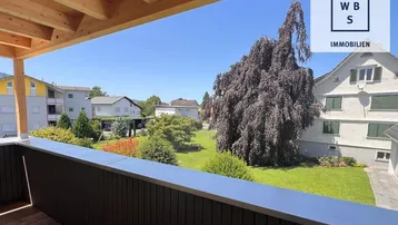 Sonniger Balkon mit Holzboden und Holzdach, bietet einen schönen Blick ins Grüne.