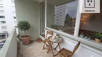 Gemütlicher Balkon mit Sitzgelegenheiten und Blick auf die umliegenden Gebäude.