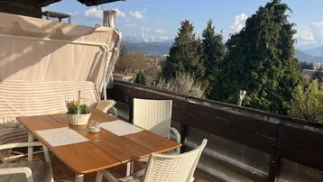 Gemütlicher Balkon mit Sitzgelegenheiten, Markise und einem weiten Blick auf die umliegende Berglandschaft.