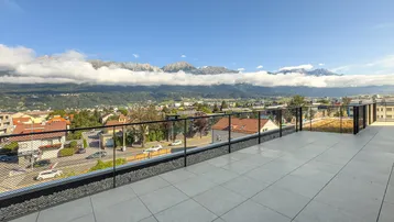 Große Dachterrasse mit Fliesenboden und weitem Blick auf die umliegende Berglandschaft.