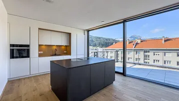 Moderne Küche mit dunkler Kücheninsel, weißen Schränken und großem Fenster mit Bergblick.