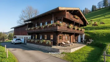Traditionelles Holzhaus im Chalet-Stil mit blumengeschmückten Balkonen, umgeben von grünen Wiesen und Bergen.
