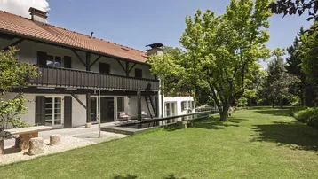 Großzügiger Gartenbereich mit Pool, Rasenfläche und der Rückseite des Hauses mit Balkon.