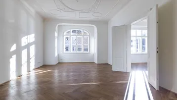 Helles, geräumiges Zimmer mit Fischgrätparkett und aufwendiger Stuckdecke, durchflutet von Sonnenlicht.