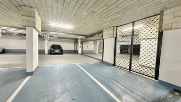 Tiefgarage mit markierten Parkplätzen und einem schwarzen Fahrzeug, durch Gittertore abgetrennt.