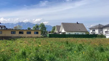 Weitläufiges Grundstück mit grüner Wiese und Blick auf die umliegende Berglandschaft.