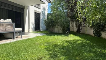 Gepflegter Rasenbereich im Garten mit üppiger Bepflanzung und angrenzender Terrasse.