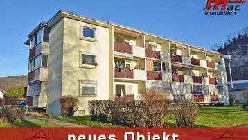 Mehrfamilienhaus mit mehreren Balkonen und gepflegter Grünfläche in sonniger Lage.