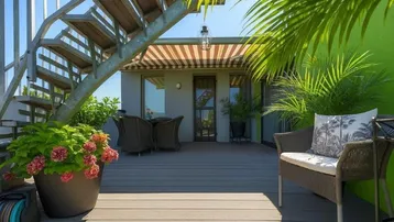 Geräumige Dachterrasse mit Holzbelag, bequemen Sitzmöbeln und einer Außentreppe zum oberen Bereich.